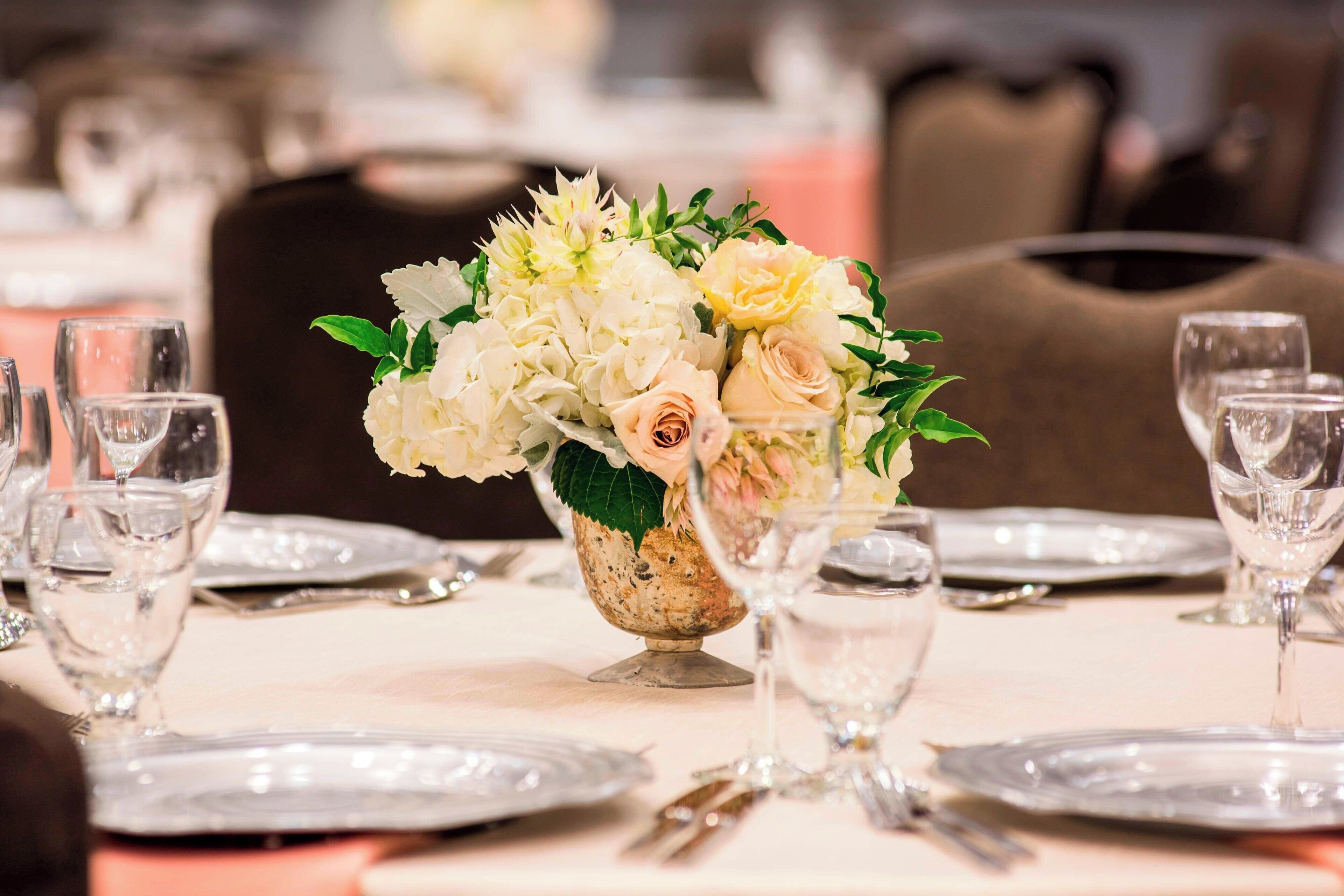 A table set for dining with a floral centerpiece, clear glassware, and plates.