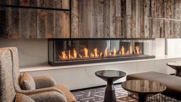 Una sala moderna con una chimenea grande, asientos cómodos y un tapiz estampado.