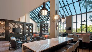 Amplia sala de estar con una mesa larga, asientos cómodos y grandes ventanales que permiten la entrada de luz natural.