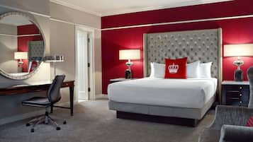 A hotel room with a large bed, a desk, a chair, and a mirror.