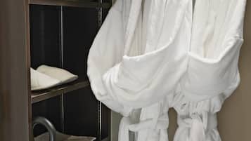 Un dressing avec des étagères pour les chaussures et les peignoirs, une tringle pour suspendre les peignoirs et un porte-serviettes.