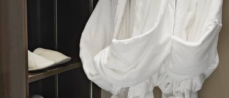 Un dressing avec des étagères pour les chaussures et les peignoirs, une tringle pour suspendre les peignoirs et un porte-serviettes.