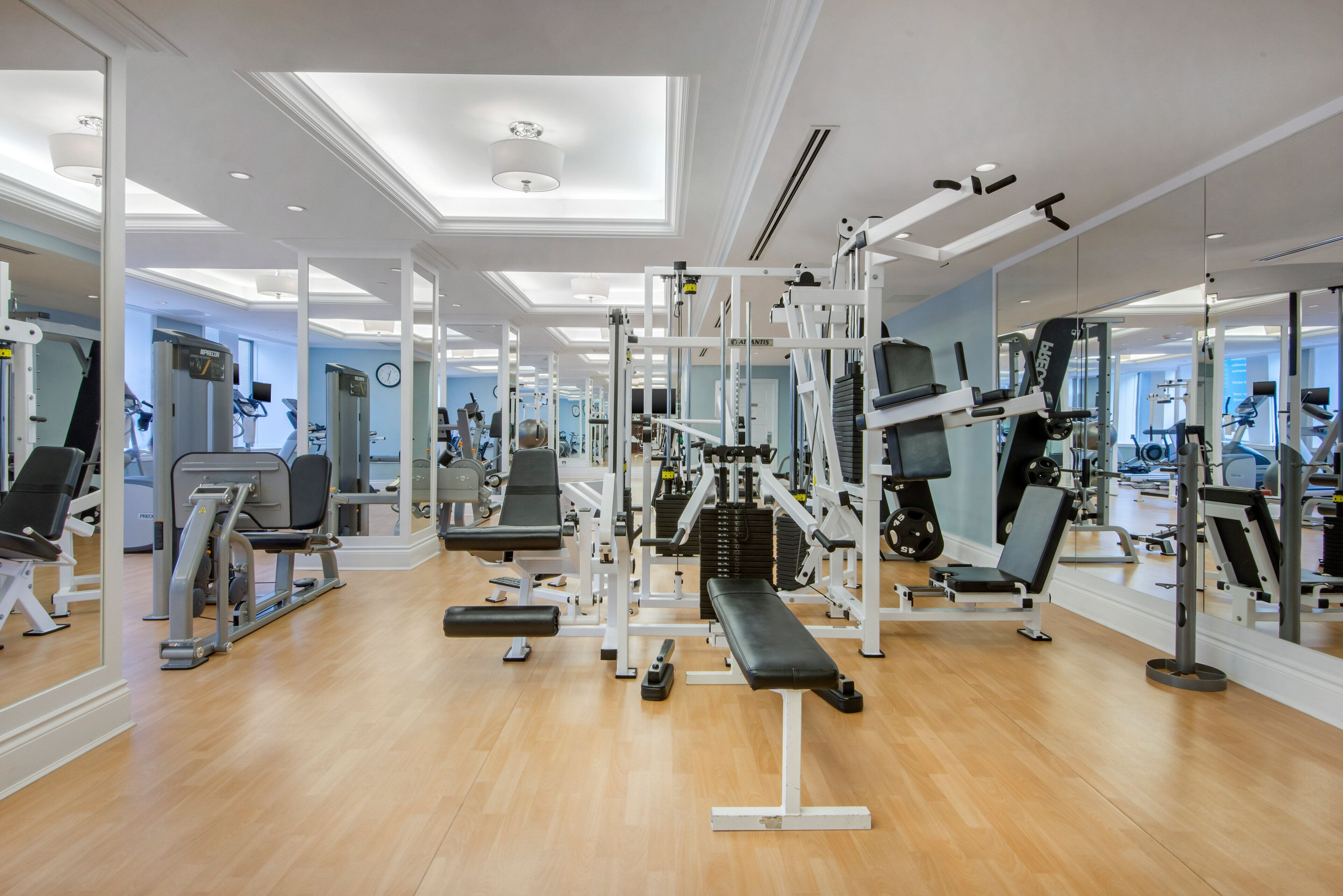 A gym with various exercise machines, wooden flooring, and mirrored walls.