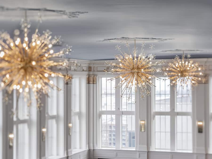A room with large windows, elegant chandeliers, and classic architectural details.