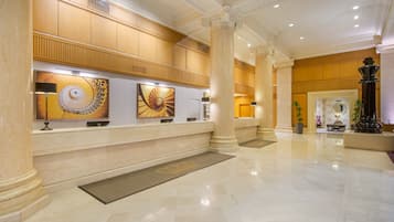A lobby with marble floors, large columns, and artwork on the walls.