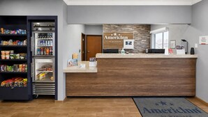 A reception area with a wooden reception desk, a refrigerator stocked with beverages, and a welcome mat.