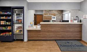A reception area with a wooden reception desk, a refrigerator stocked with beverages, and a welcome mat.