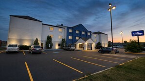 A hotel with a parking lot and a building with multiple floors and a blue accent.