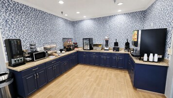 Una cocina con armarios azul oscuro, encimera de granito y salpicadero con estampado.