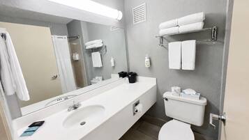 A modern bathroom with a large mirror, a double sink, a toilet, and towel racks.
