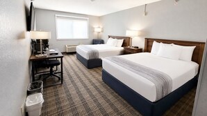 A hotel room with two beds, a desk, a chair, a trash bin, and a window. - AmericInn by Wyndham Minot (Minot)