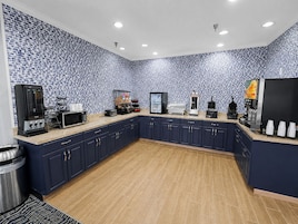 Una cocina con salpicadero de diseño azul y blanco, armarios azul oscuro y varios electrodomésticos, incluyendo una cafetera y un microondas.