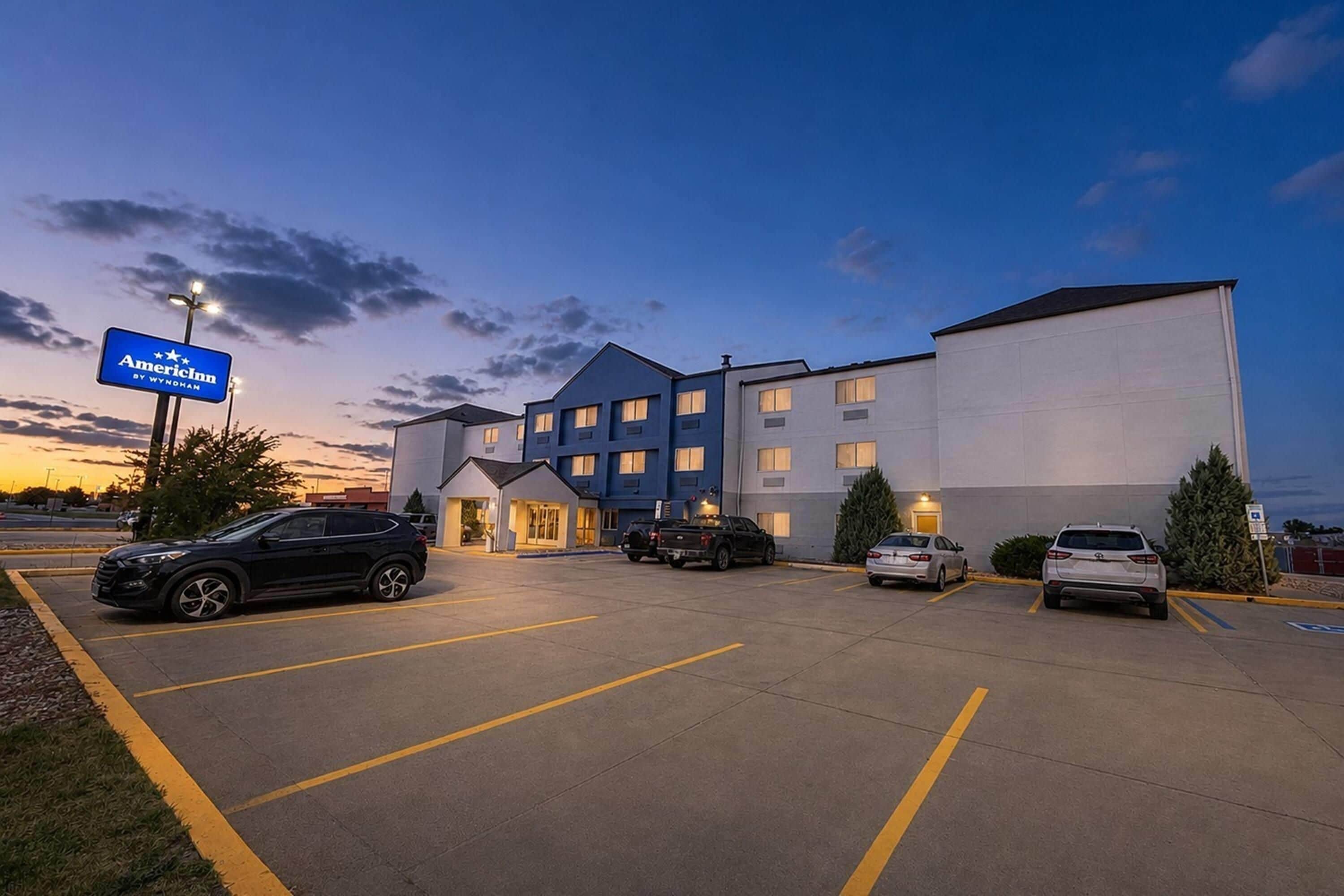 Un hotel con parcheggio, diversi edifici e una segnaletica che indica che si tratta di un AmericInn by Wyndham.
