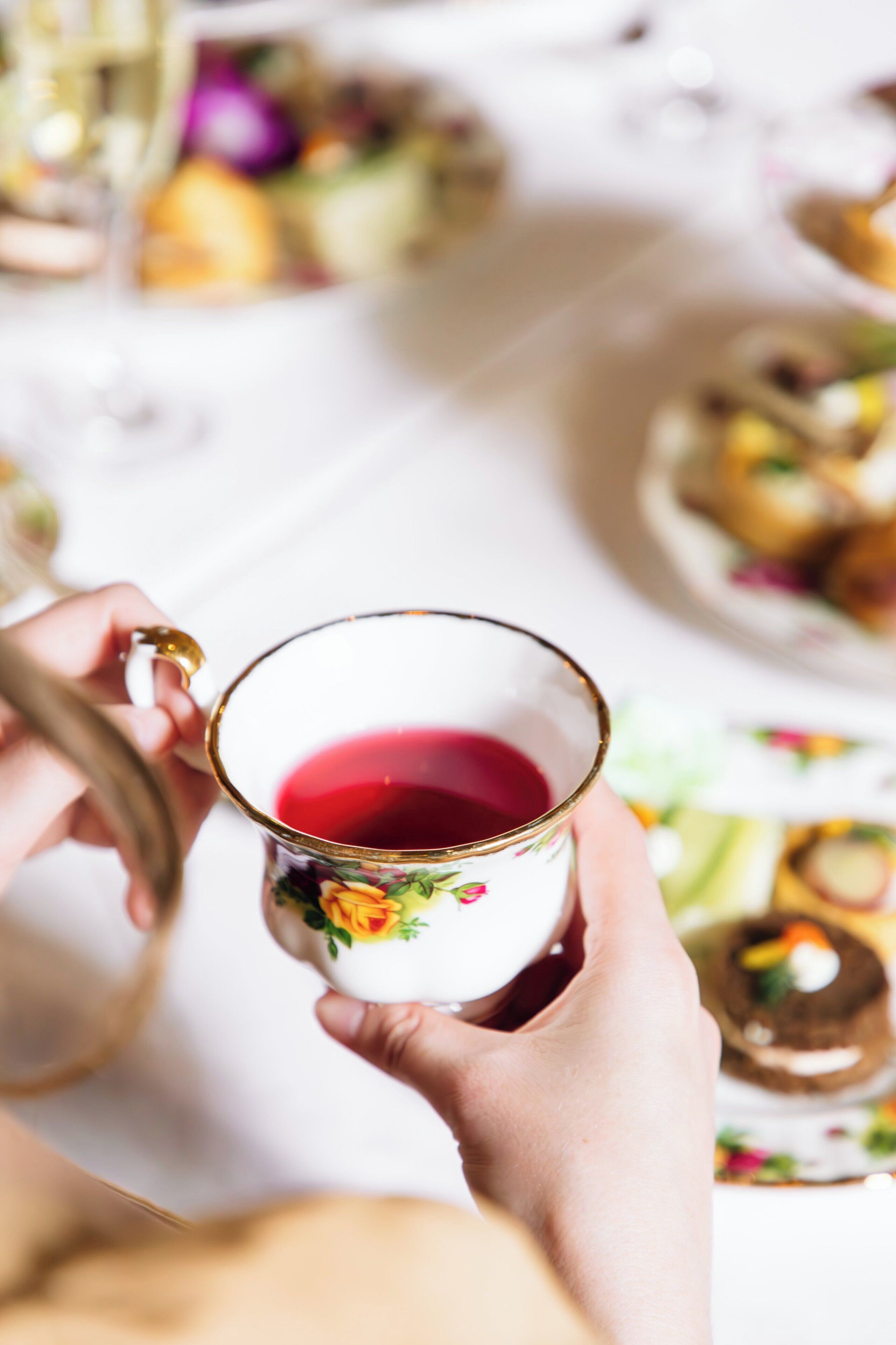 A hand holding a cup with a floral pattern.