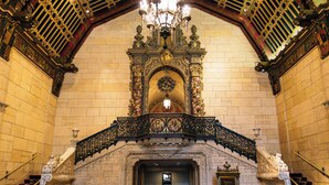 An ornate hotel lobby with a grand chandelier, intricate wall decorations, and a staircase leading to the upper levels. - The Biltmore Los Angeles (Los Angeles)