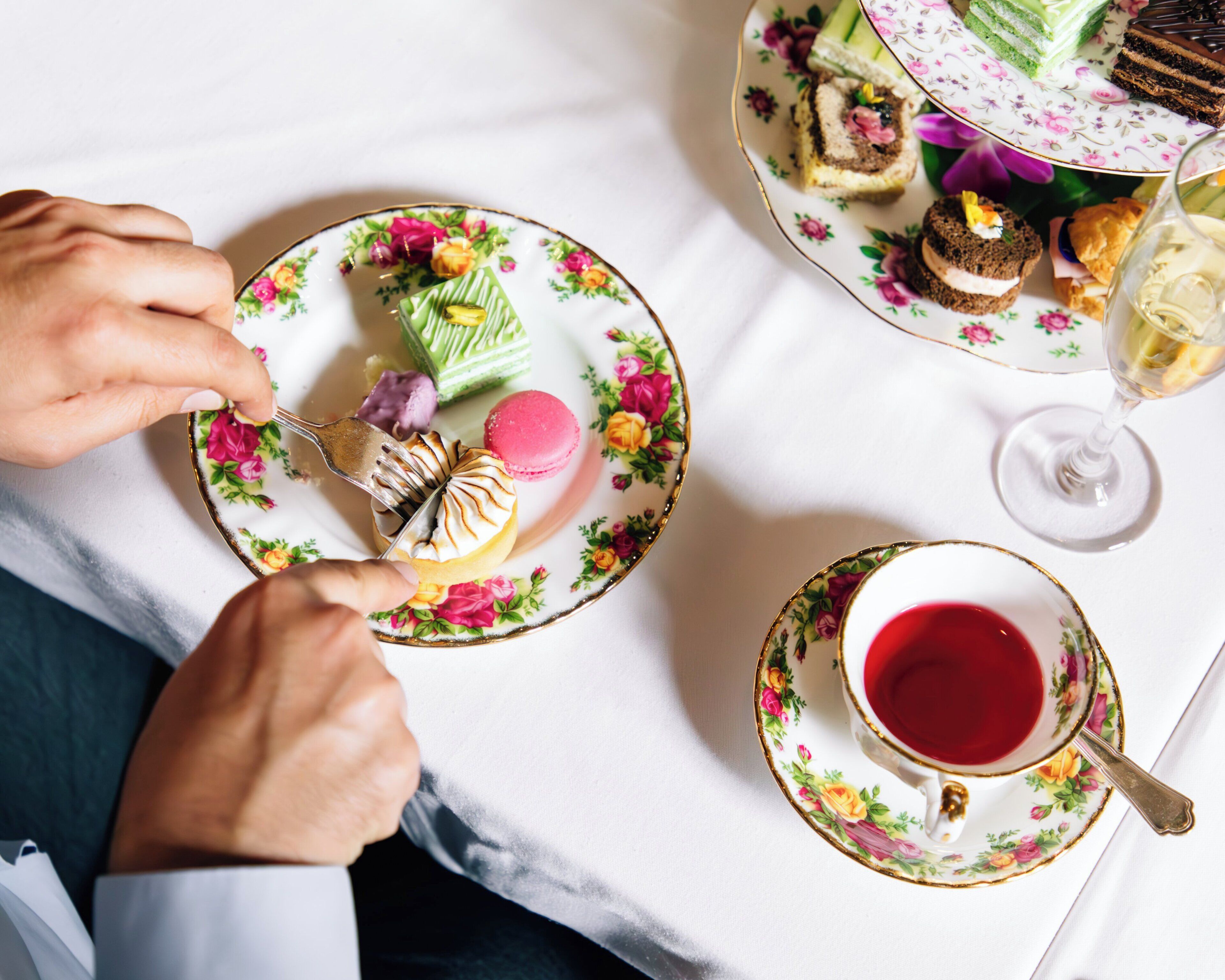 A table with a floral-patterned plate, a glass of red liquid, and a fork with food.