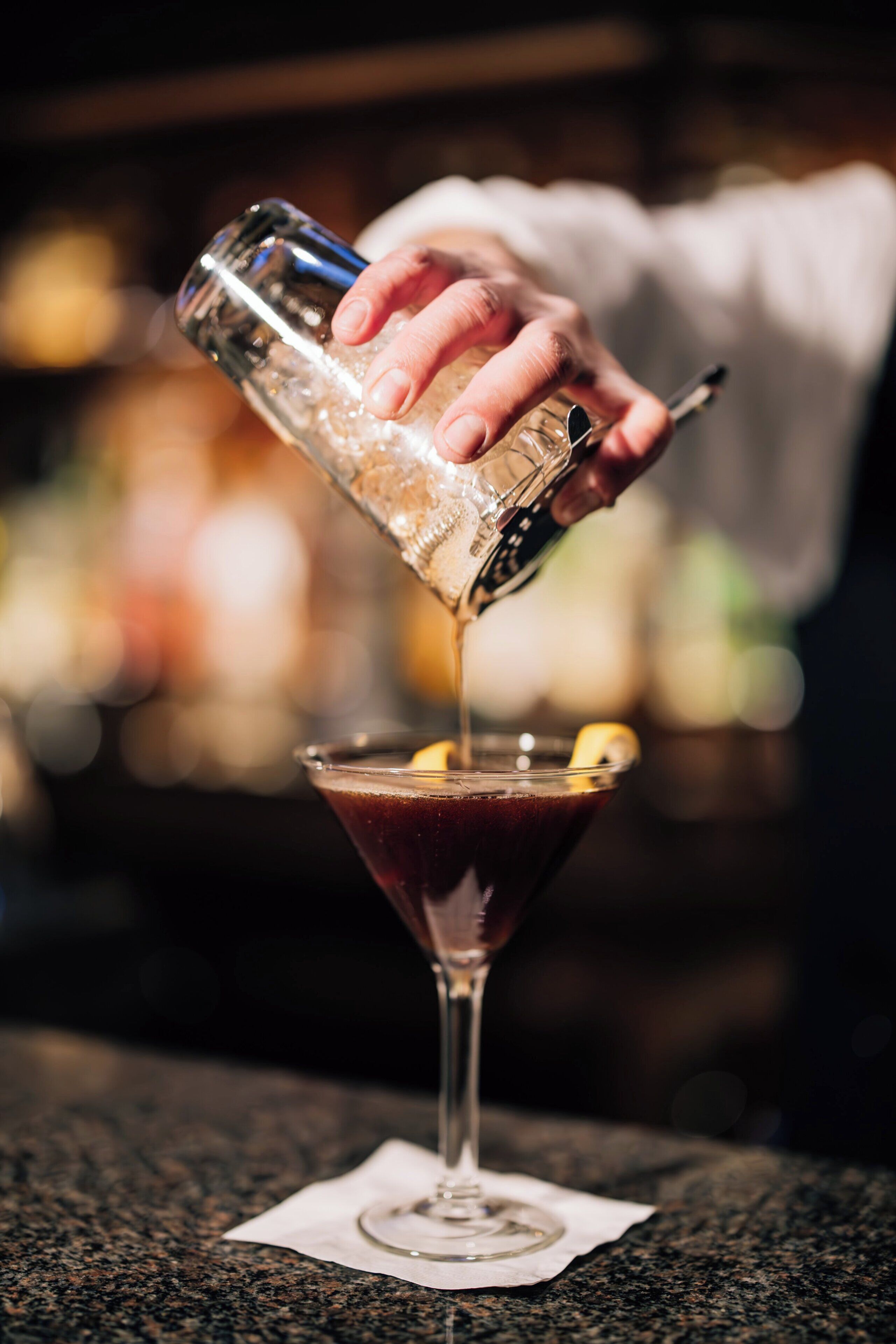 Una mano sirviendo una bebida en una copa de martini.