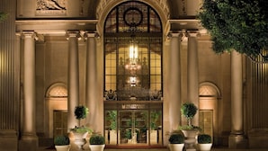 Une entrée imposante, ornée de colonnes, une grande fenêtre en arc de cercle et une enseigne indiquant l’hôtel Millennium Biltmore.