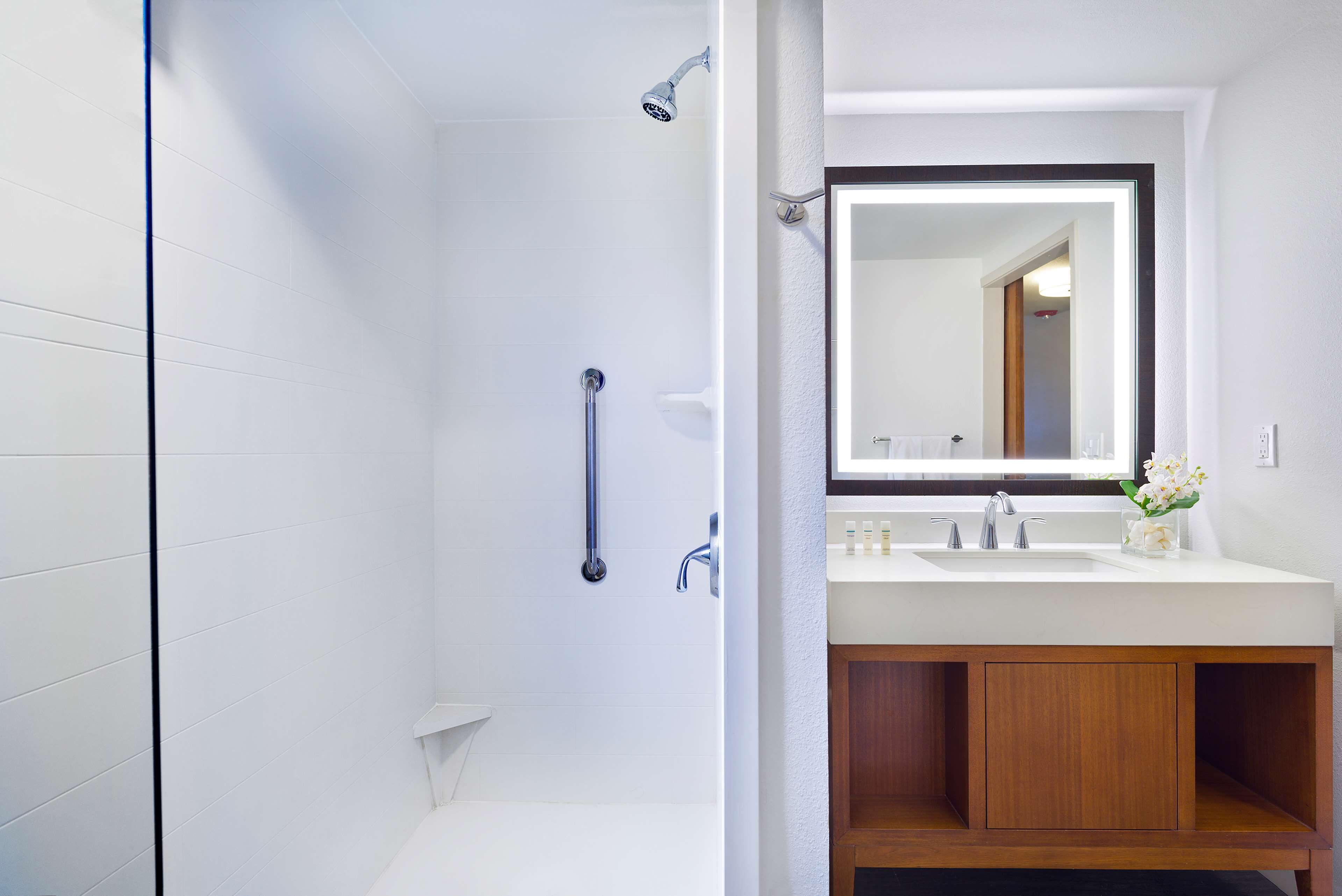 A modern bathroom with a shower, a sink with a mirror, and wooden cabinetry.