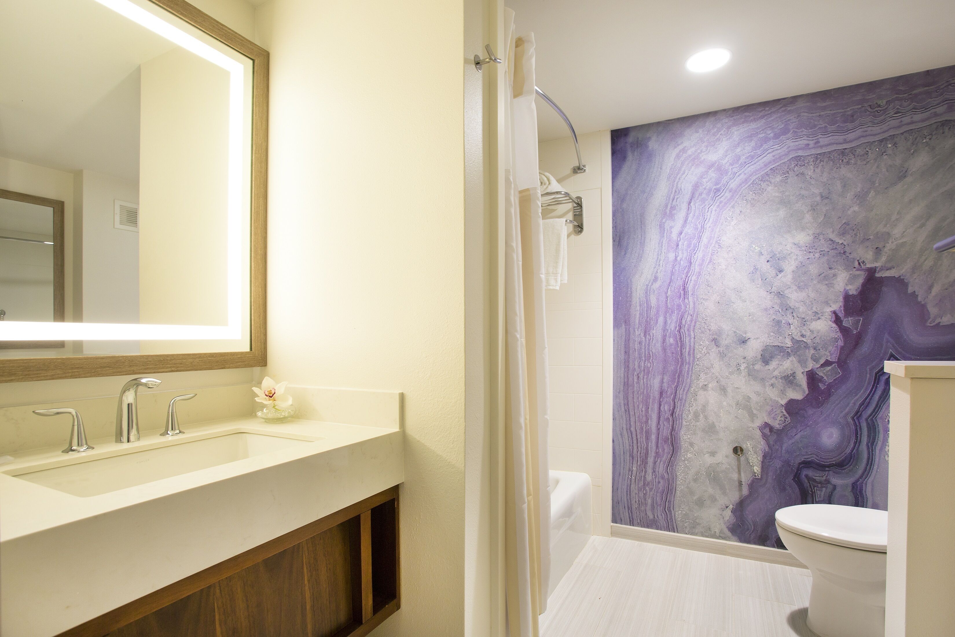 Un baño con un espejo grande, un lavabo, una ducha y un inodoro.