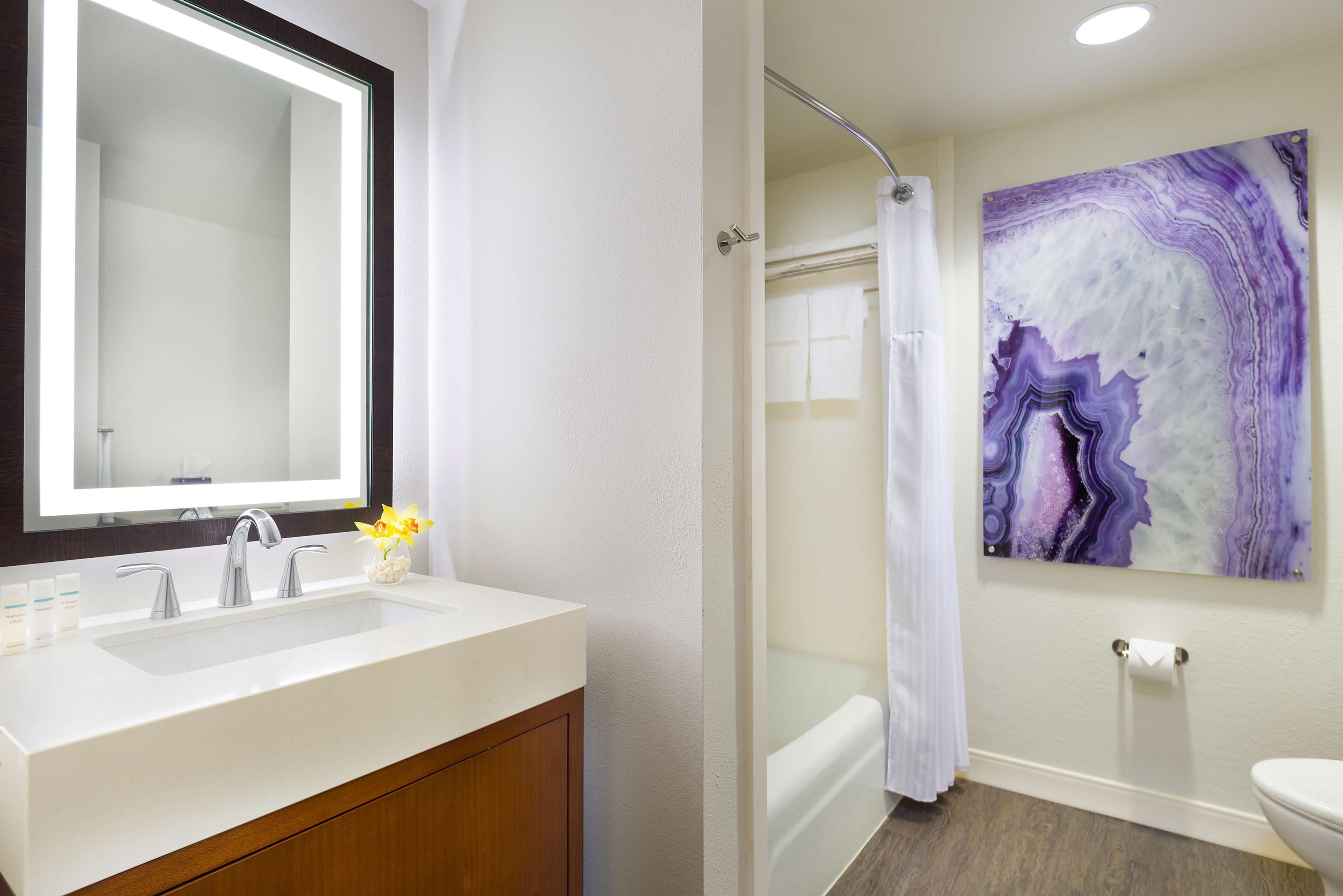 A bathroom with a white sink, mirror, and shower curtain.