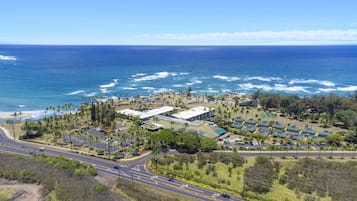 Vista aérea de un complejo turístico costero con varias edificaciones, una carretera y una playa.
