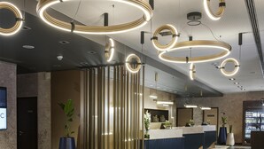 Un espace d’accueil moderne avec un comptoir d’accueil incurvé, des luminaires verticaux et un sol à motifs.
