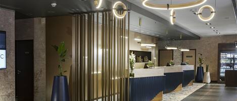 Un área de recepción moderna con un mostrador curvo, luminarias verticales y un suelo estampado.