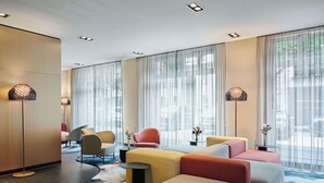 Un hall d’hôtel moderne doté d’un espace salon, de grandes fenêtres et de lampes décoratives.