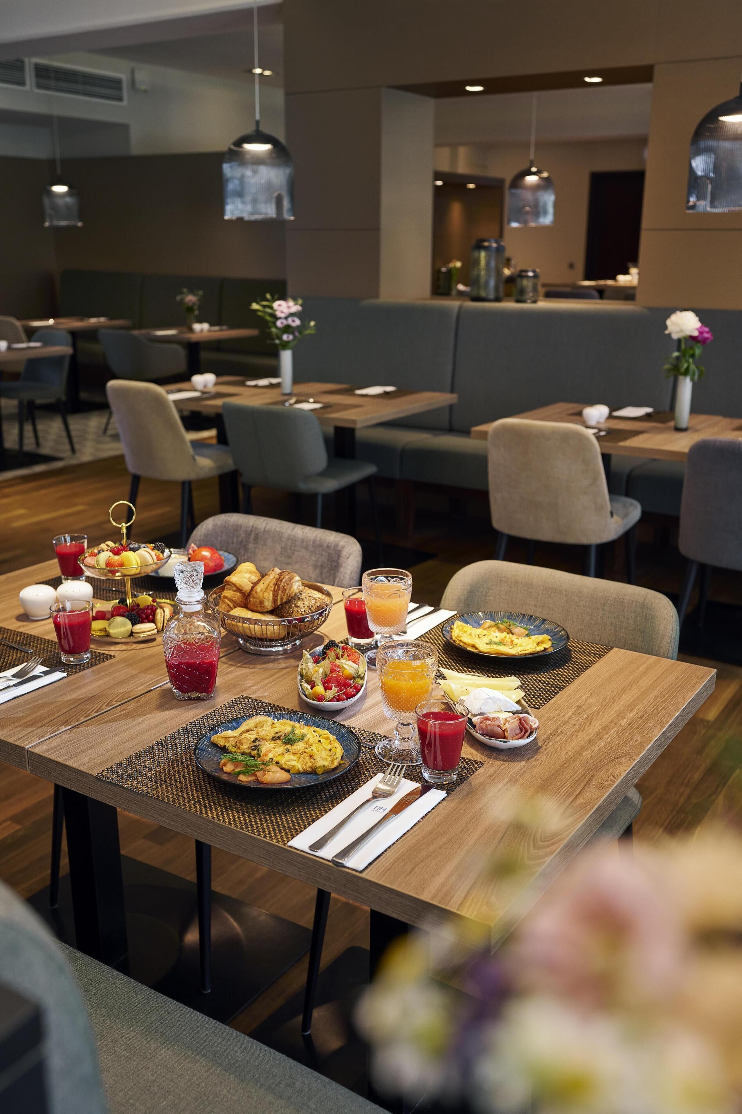 Et morgenbord med forskellige retter, drikkevarer og en vase med blomster på et bord.