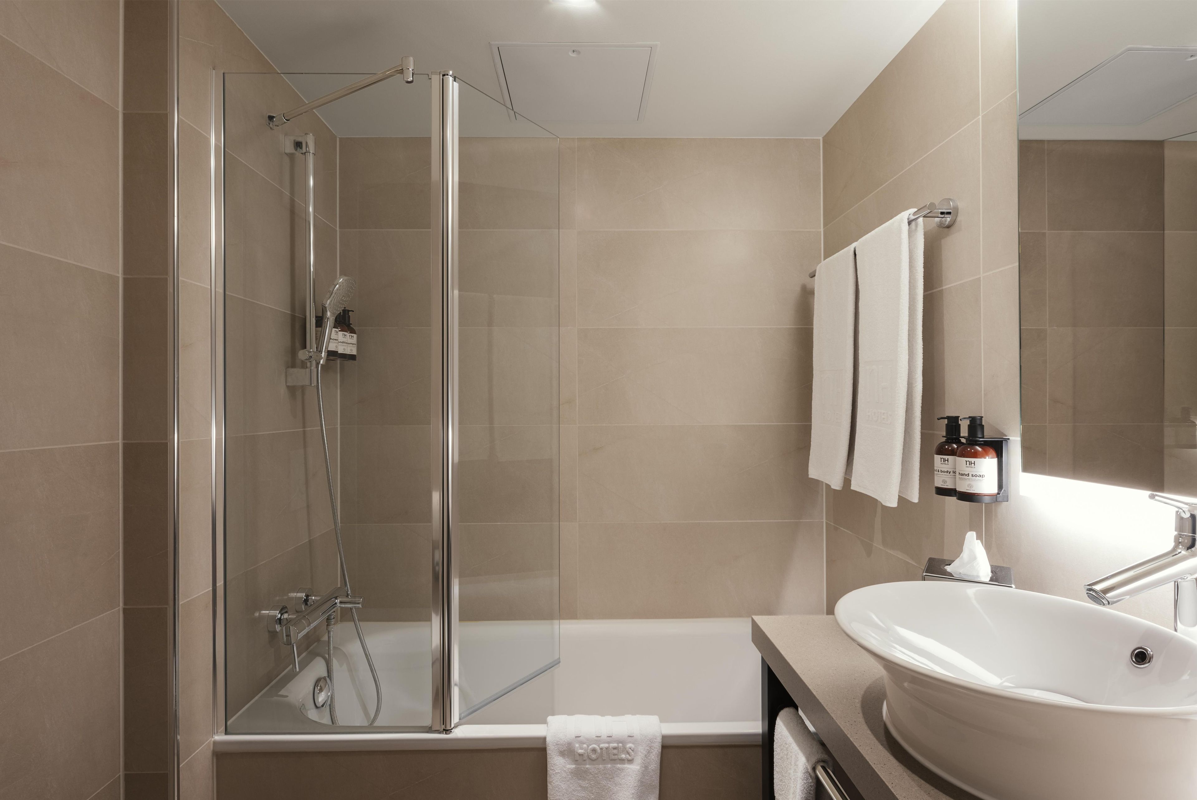 Une salle de bain moderne avec une douche à parois de verre, une baignoire et un lavabo avec un miroir.