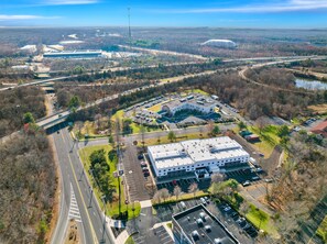 An aerial view of a commercial area with a large building, parking lots, and surrounding roads.