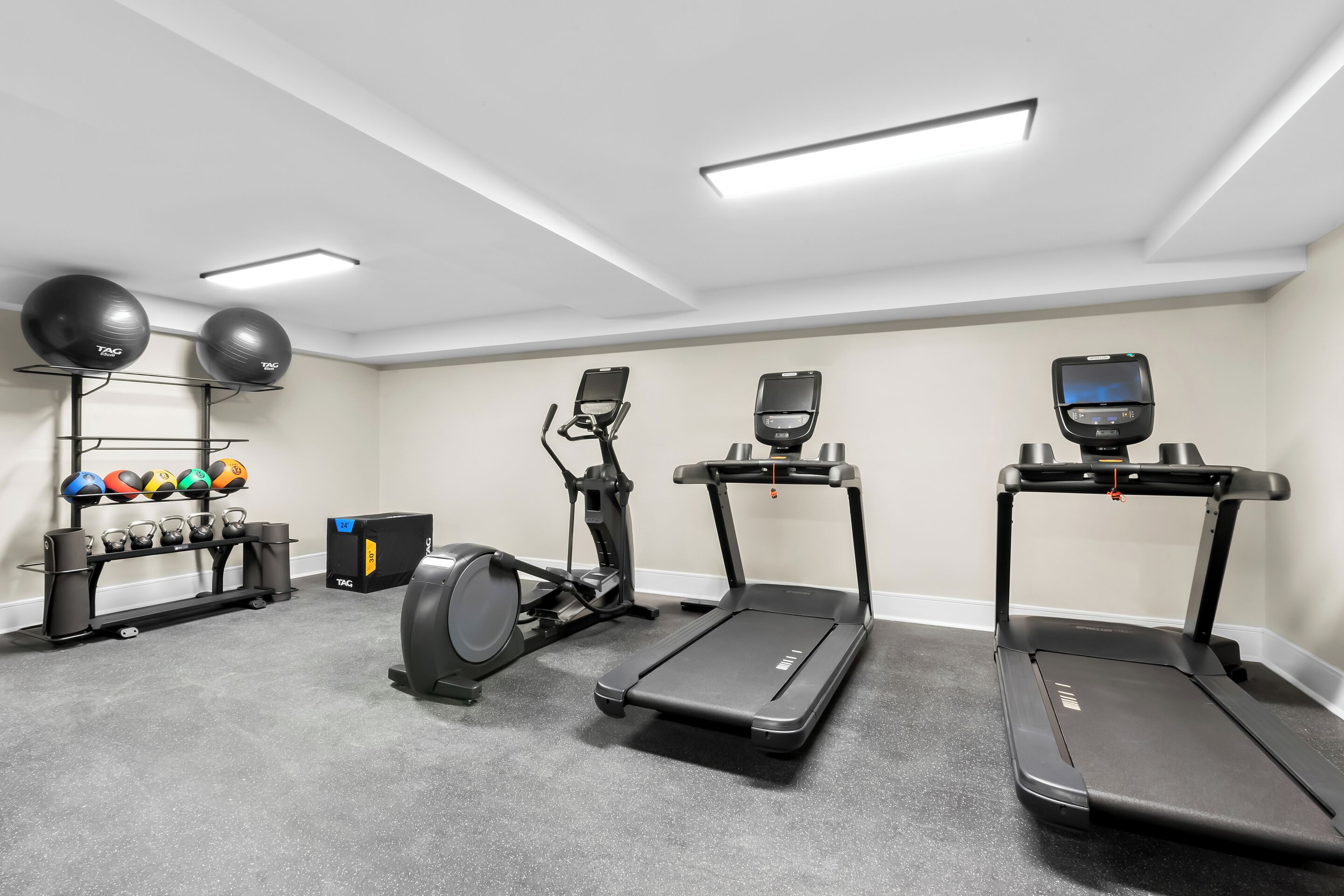 Ein Heimfitnessraum mit Laufbändern, Crosstrainern und einem Gewichtsständer.