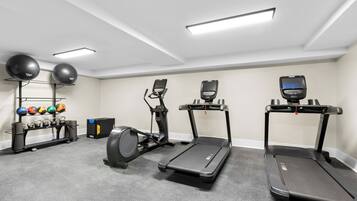 Ein Heimfitnessraum mit Laufbändern, Crosstrainern und einem Gewichtsständer.