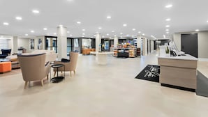 Un hall d’entrée spacieux, doté de meubles modernes, d’un comptoir de réception et d’un plafond bien éclairé.