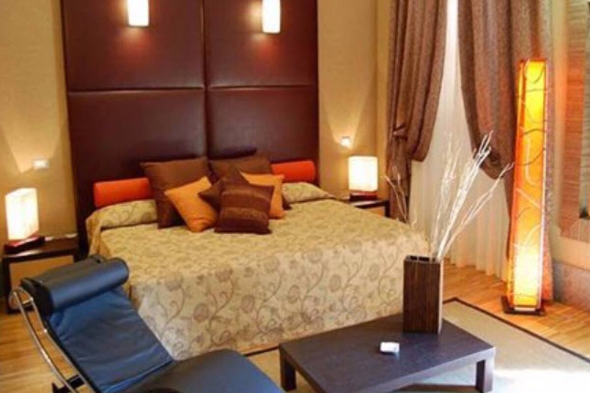 A hotel room with a bed, bedside tables, a desk, and a chair.