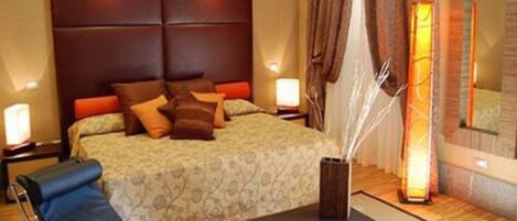 A hotel room with a bed, bedside tables, a desk, and a chair.