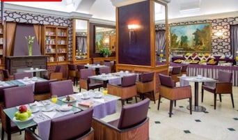 A restaurant with multiple tables and chairs, a bookshelf, and a painting on the wall.