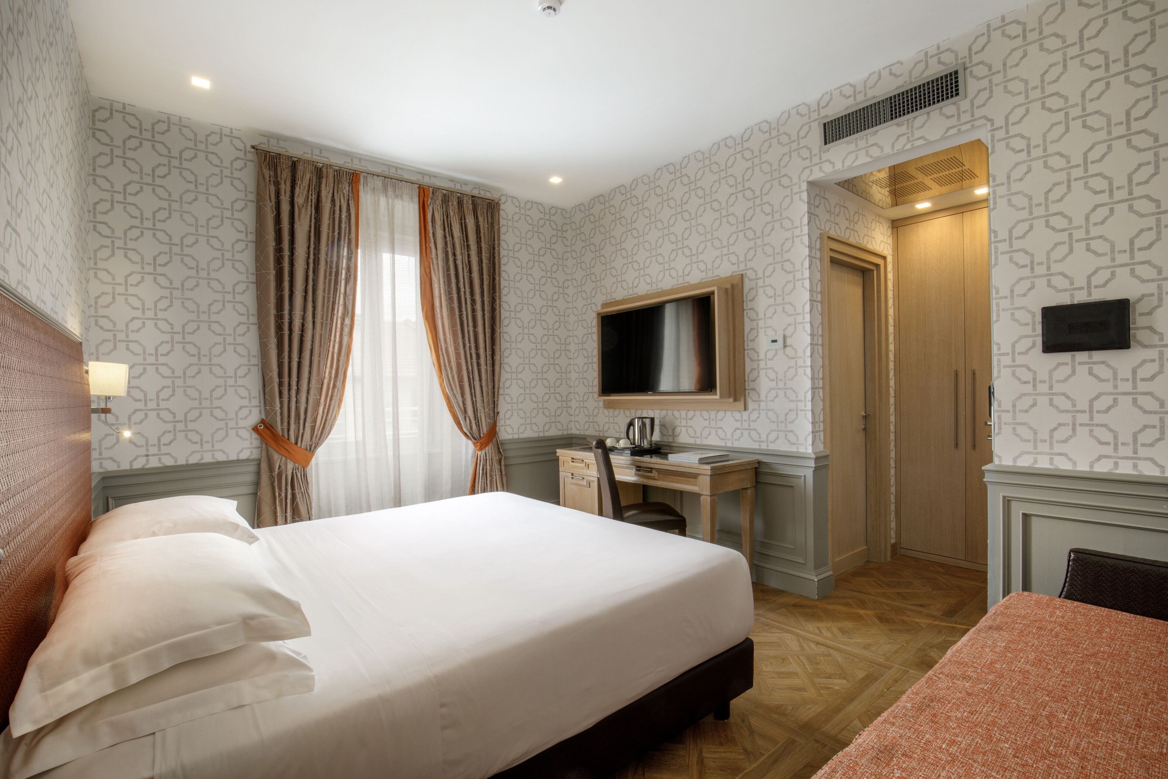 Une chambre d’hôtel avec un grand lit, un bureau avec une chaise, une télévision et une armoire.