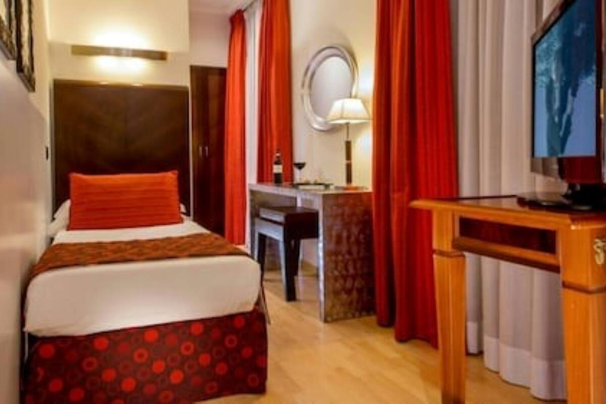A hotel room with a bed, a desk, a chair, a TV, and a mirror.
