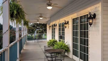 A covered patio with ceiling fans, a table with chairs, and potted plants.