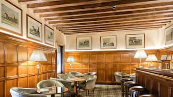 Zona bar con rivestimenti in legno, tappeto a scacchi e sgabelli da bar.