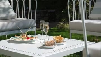 A white table with a floral pattern, set outdoors with white metal chairs.