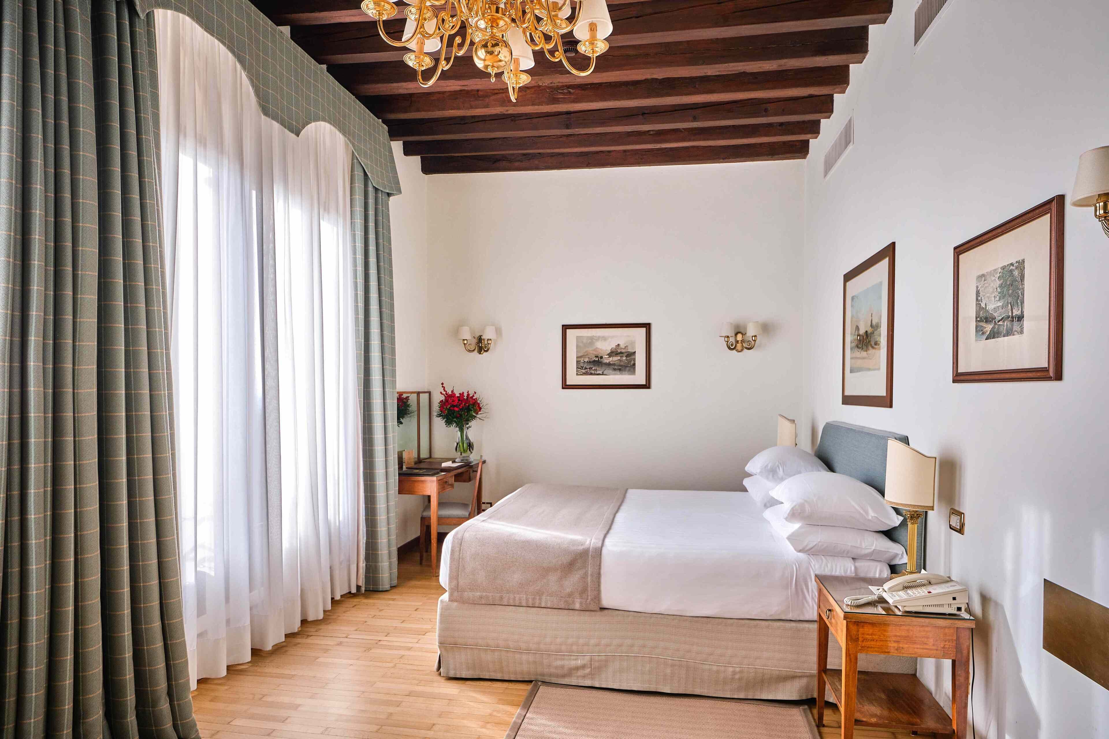 A hotel room with a bed, bedside table, lamp, and framed pictures on the wall.
