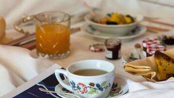 Colazione in camera: una tazza di caffè, un bicchiere di succo d'arancia e un piatto di cibo.