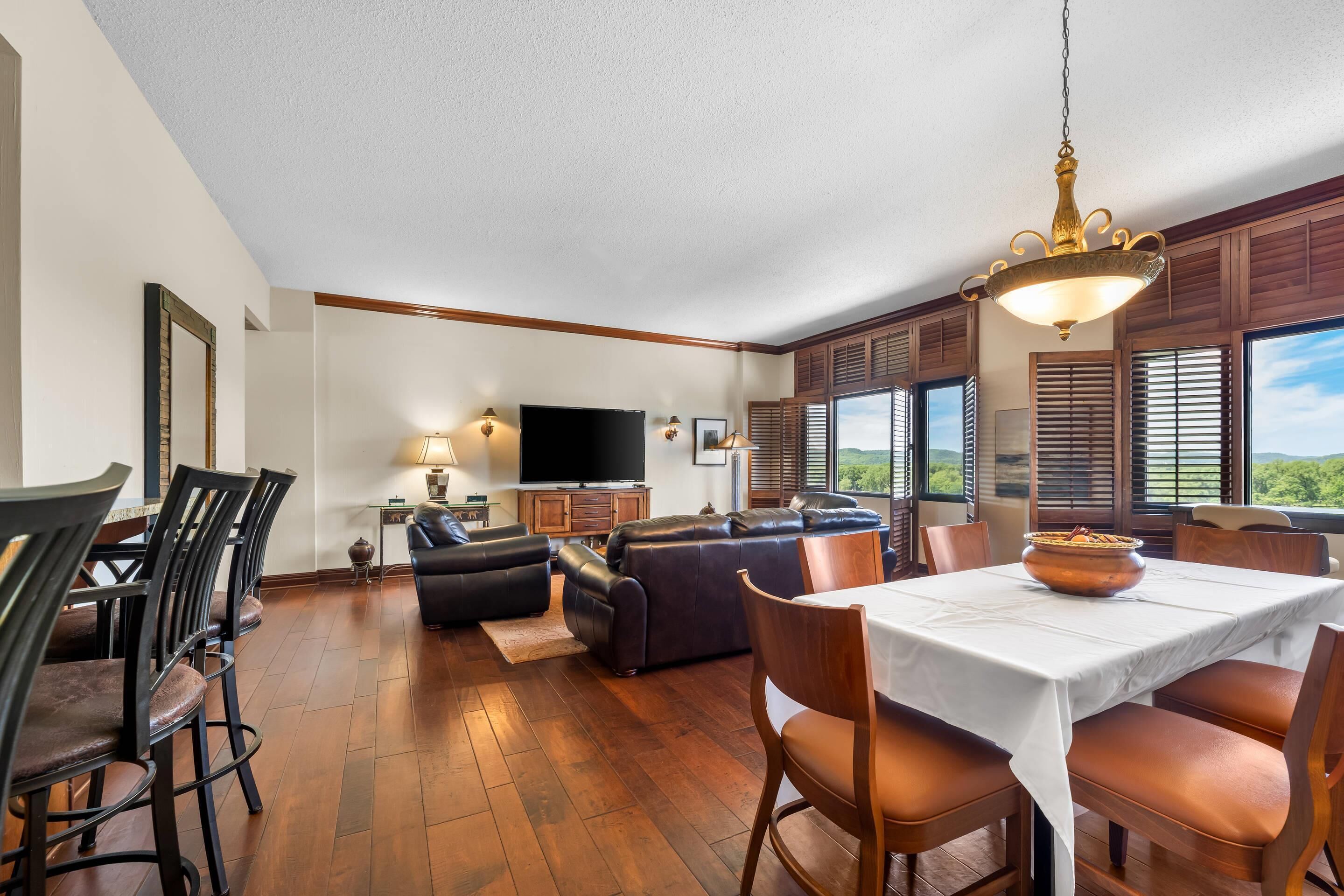 A spacious living area with a dining table, sofas, and a TV.