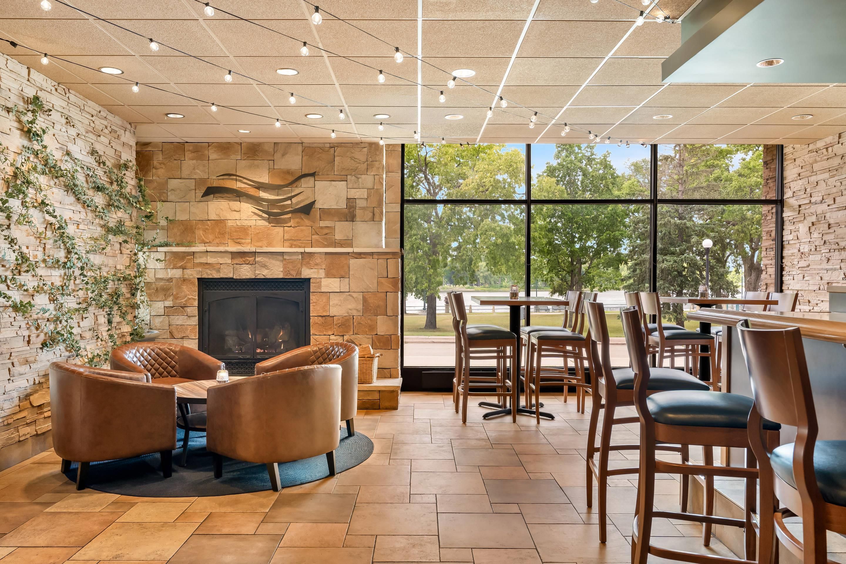 A modern interior with a fireplace, stone walls, and a view of the outdoors.
