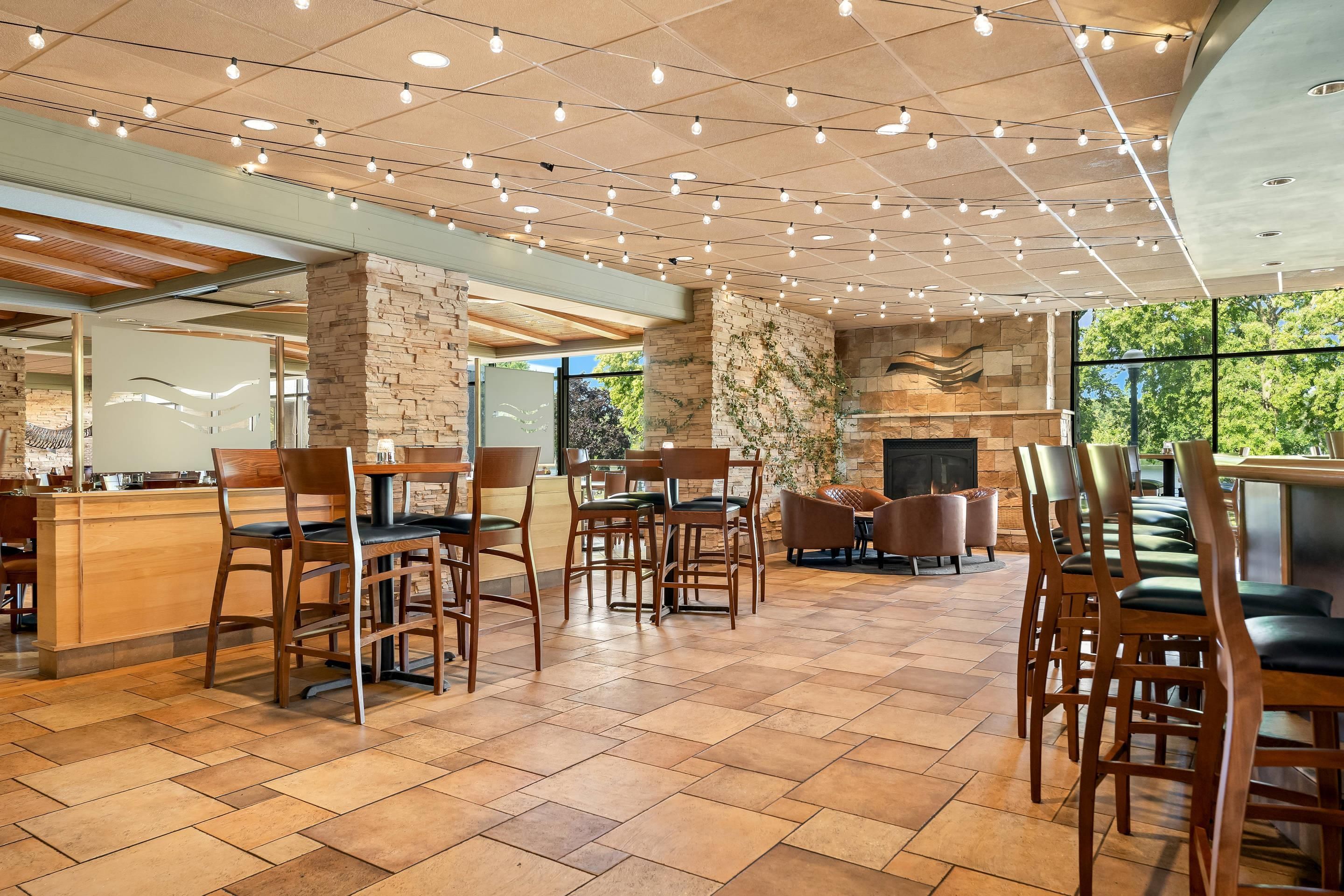 Restaurante com parede de pedra, cadeiras de madeira e chão de azulejos.