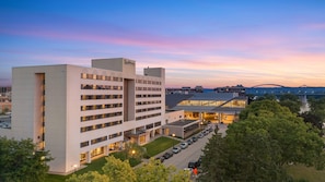 A multi-story hotel with a parking lot and a view of a bridge in the background. - Radisson Hotel La Crosse (La Crosse)