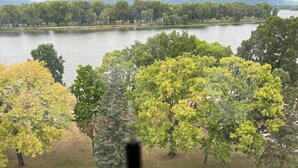 Vista de un lago con árboles y una botella de vino sobre una mesa.